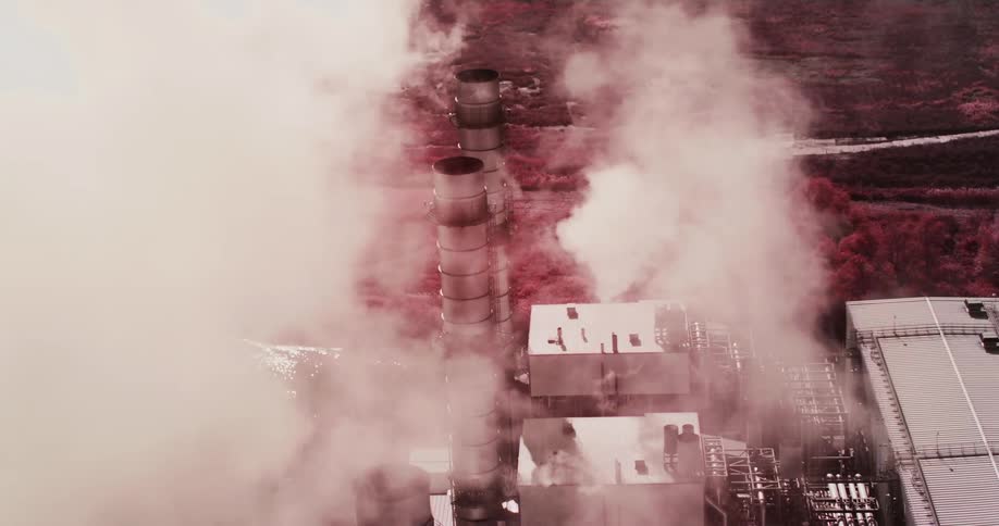 Steam billows upwards from tall smoke stacks at a large industrial facility