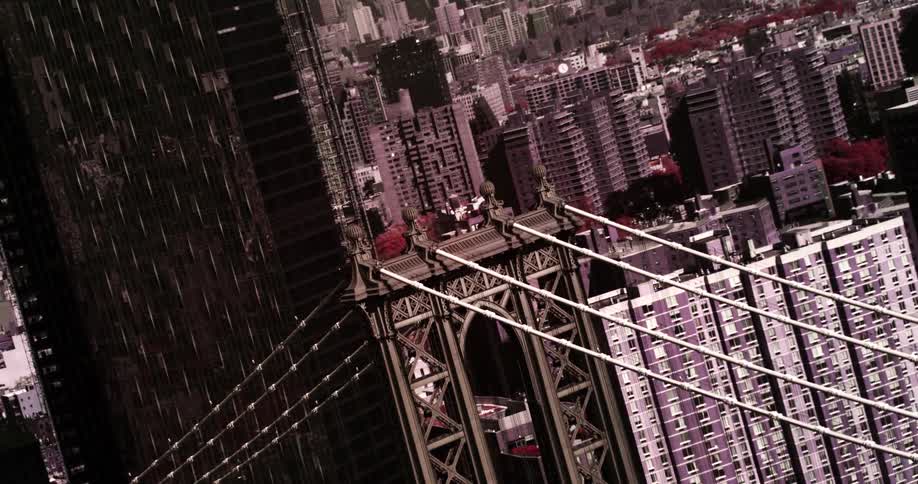 A suspension bridge sits in the midst of a large downtown urban area