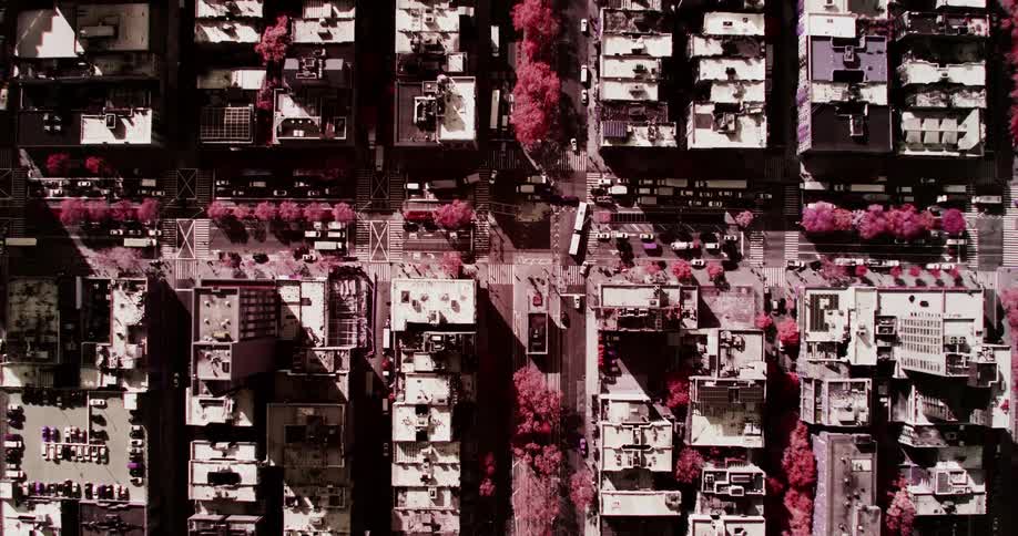 Several parked vehicles line the streets between buildings in an urban area