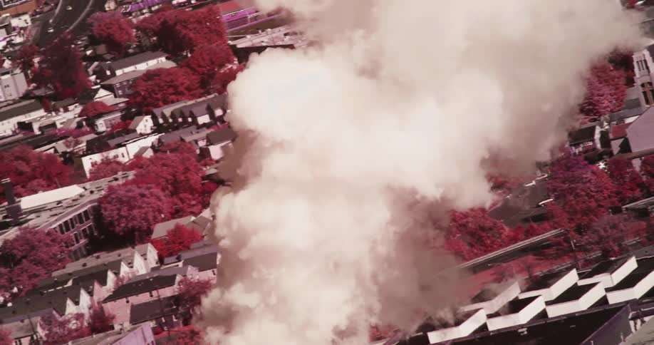A pillar of smoke in front of a neighborhood in a city