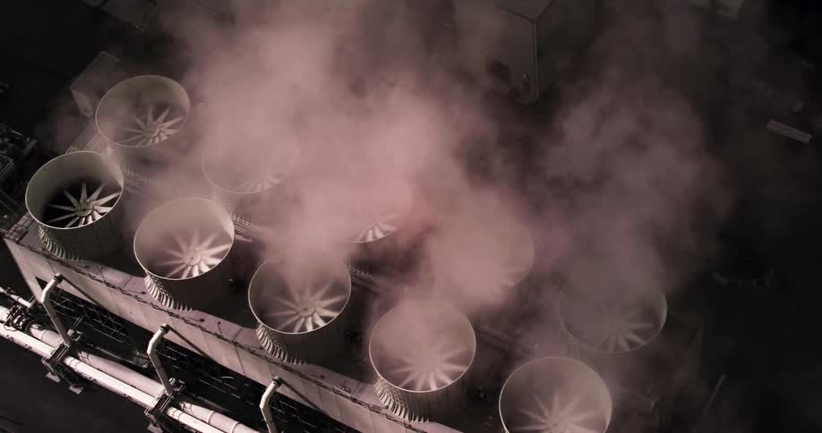 The rooftop of a factory with rows of fans blowing steam