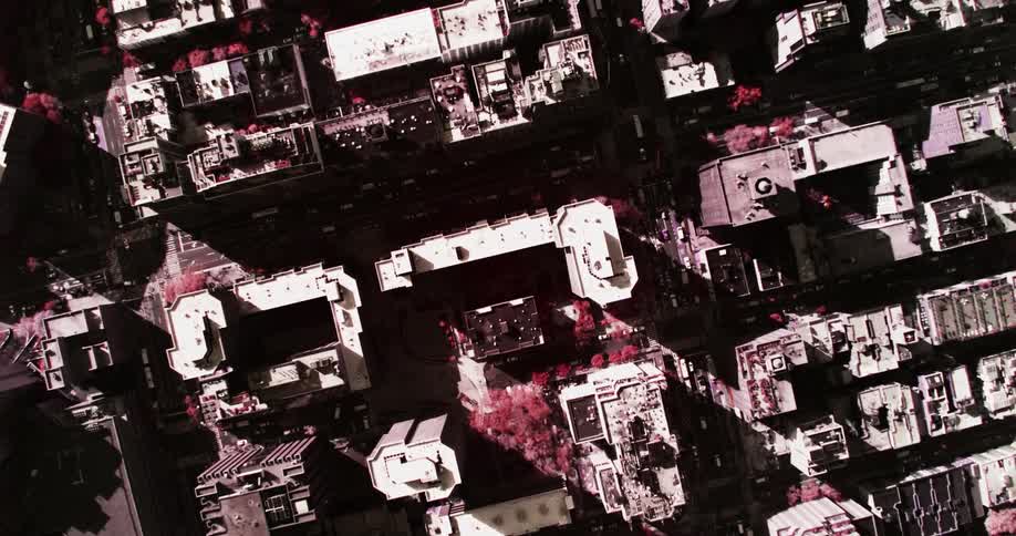 An aerial view of an urban area is densely filled with many tall buildings and streets filled with vehicles
