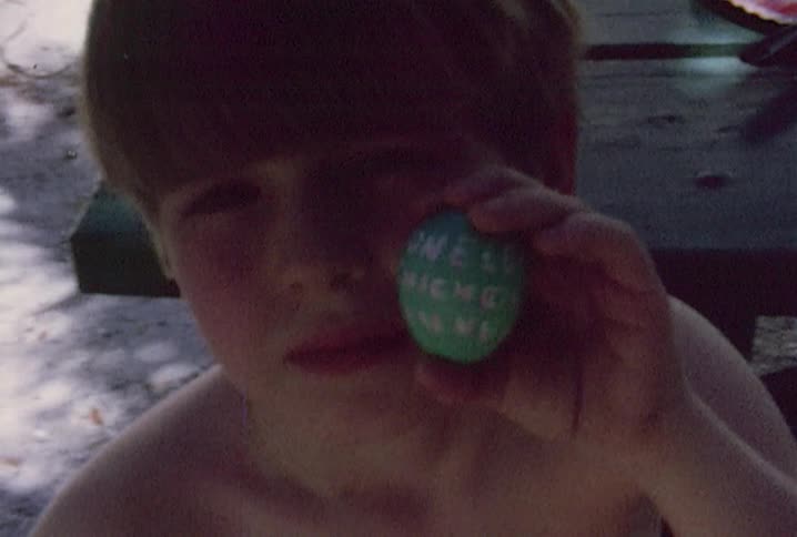A boy holding a green egg with words carved on it