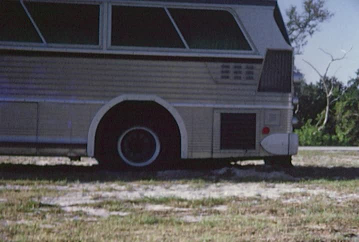 The rear tire of a bus is stuck in the mud