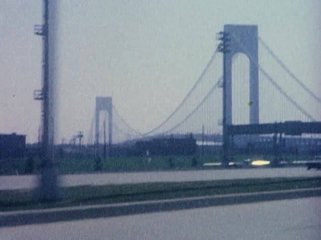 Cars travel along a road next to a large bridge