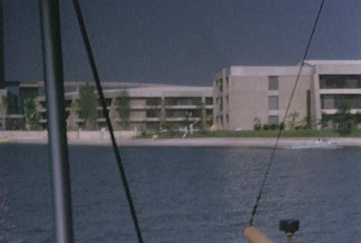 Boats travel through the water next to apartment buildings