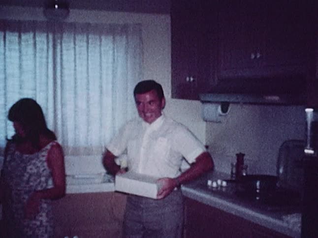 A man and woman pose for a picture in the kitchen