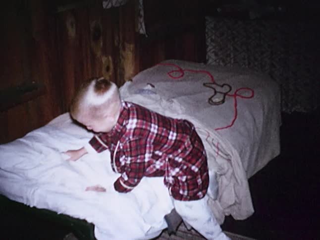 Boy in a plaid robe climbing into a bed