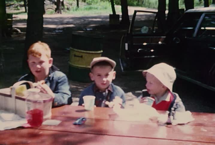 Three children eating lunch at a park bench