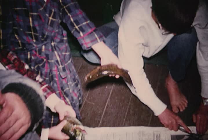 A group of boys skinning and gutting fish
