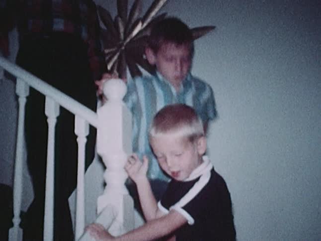 A man and two young boys descend the staircase of a home