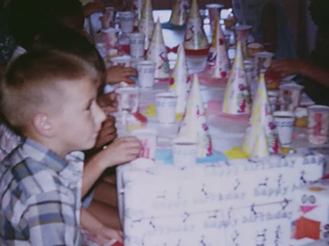 Children sit at a table decorated with party hats and favors
