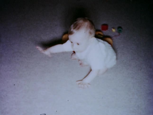 A baby sitting and crawling on the carpet