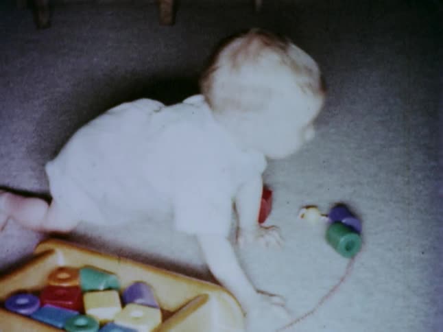 A crawling baby moves a toy out of his way
