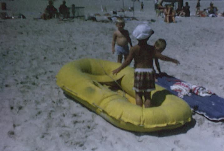 Three little boys playing on some water rafts
