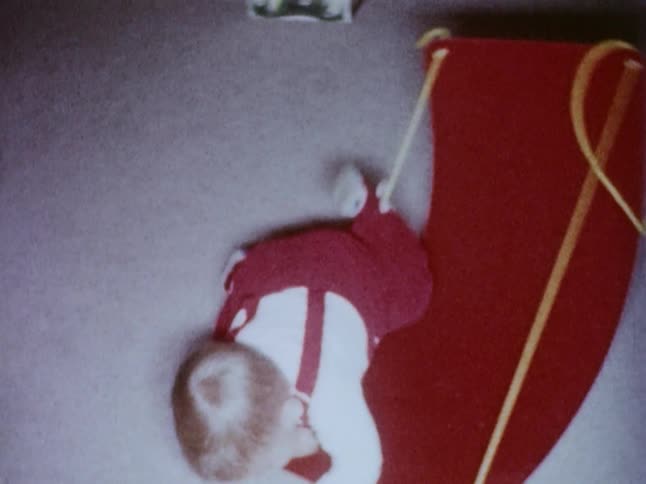 A toddler walks and crawls around a living room