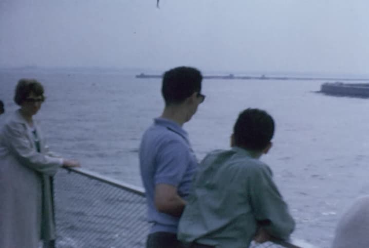 A crowd of tourists ride a ferry boat as it goes past the statue of liberty
