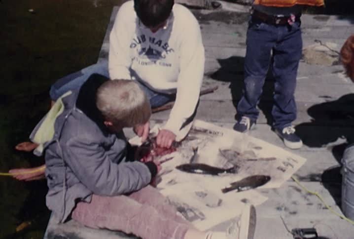People are cutting fish on some newspaper