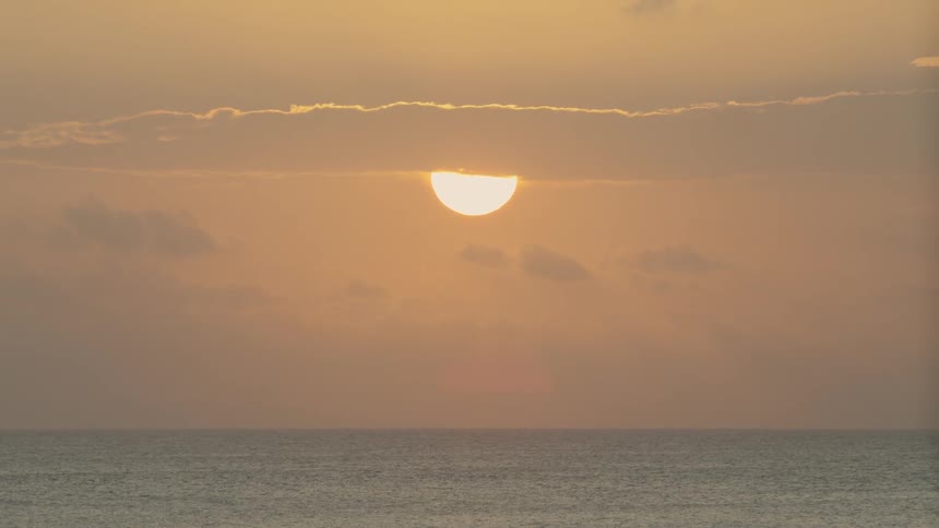 The ocean with the sun and clouds in the background