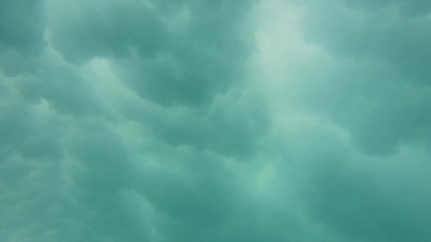 From beneath the surface of the ocean a large wave swiftly passes overhead