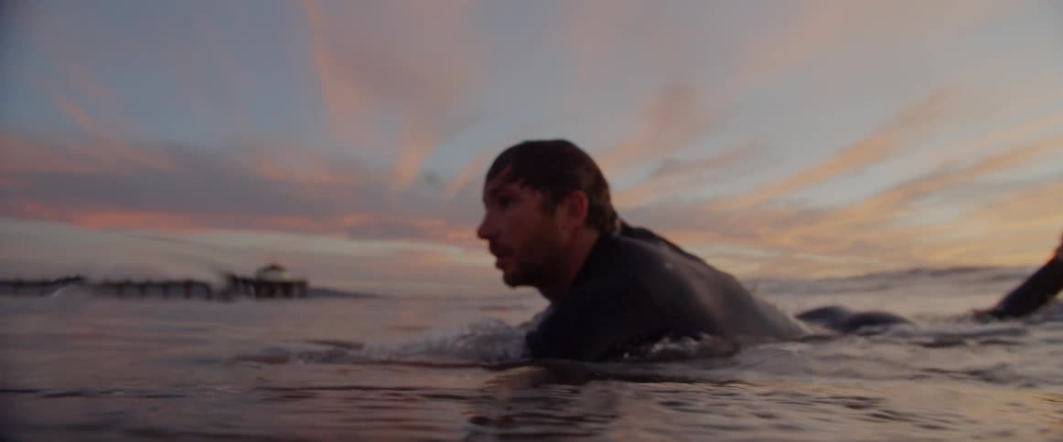 White man surfing at the ocean during dusk