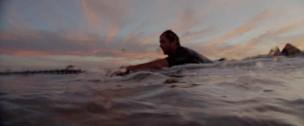A man paddles on his surfboard in the water