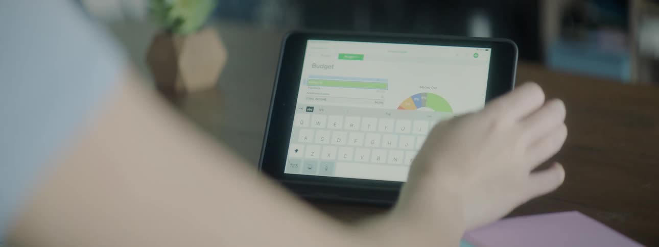 A woman sitting at a table using a tablet on a stand