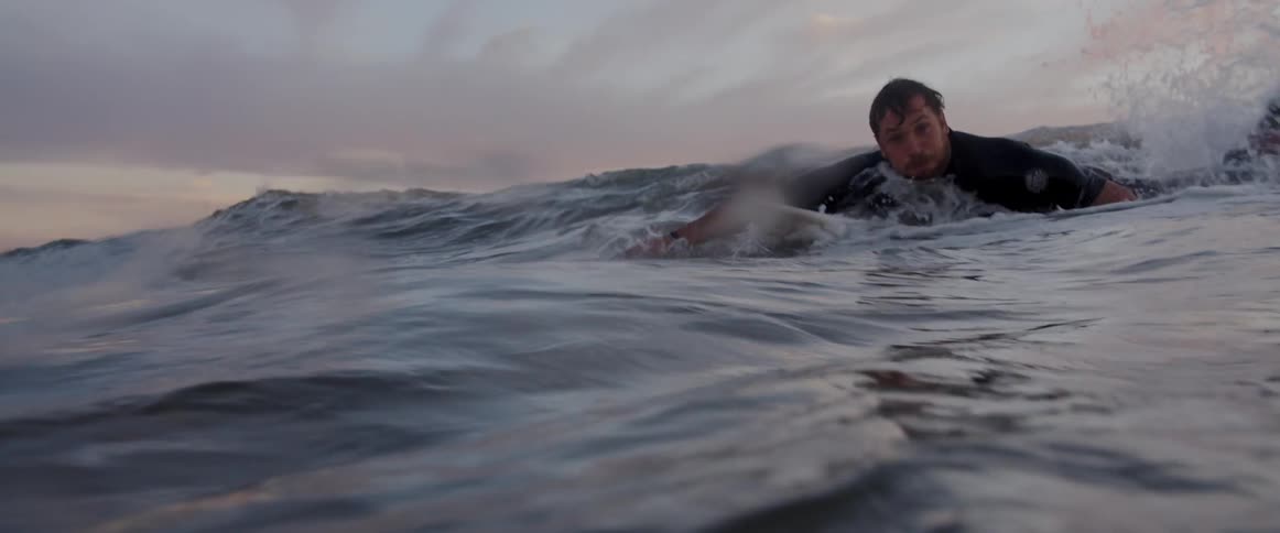 A surfer swimming through the waves on his surfboard