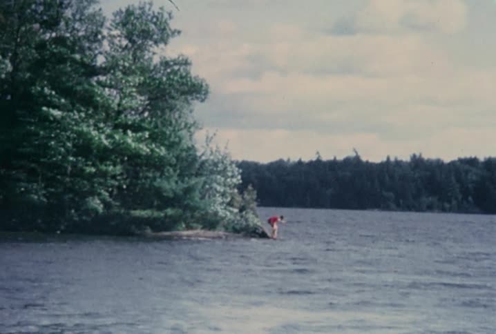 Old footage of someone getting into choppy water on a cloudy day