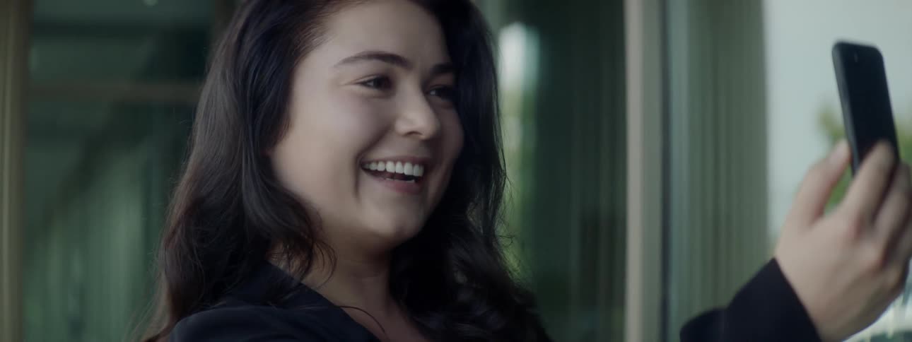 A woman smiles at her phone