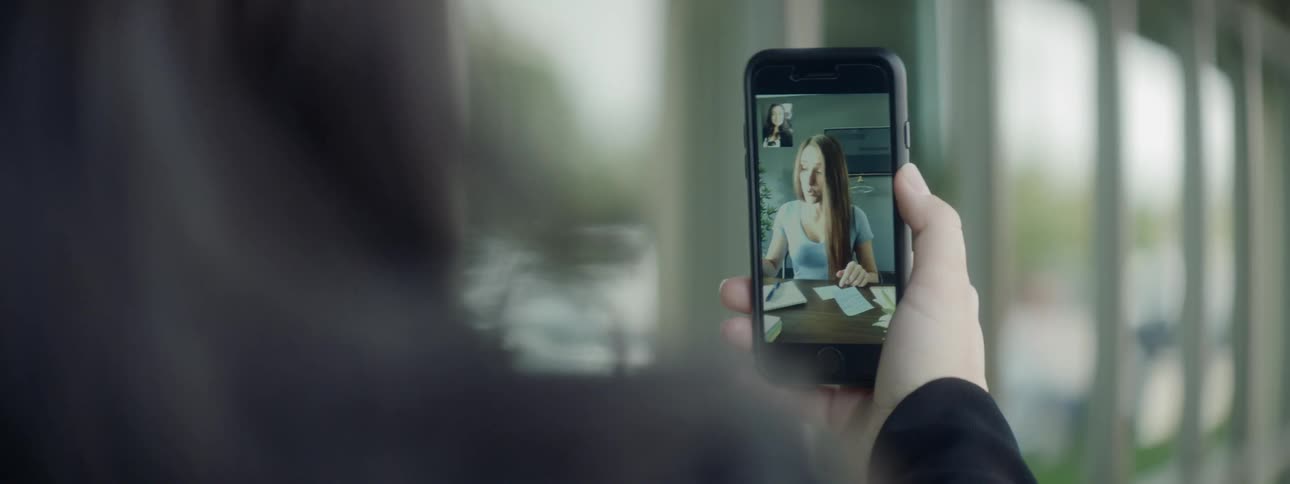 A woman holds up a smart phone in front of her as she has a video chate with another woman