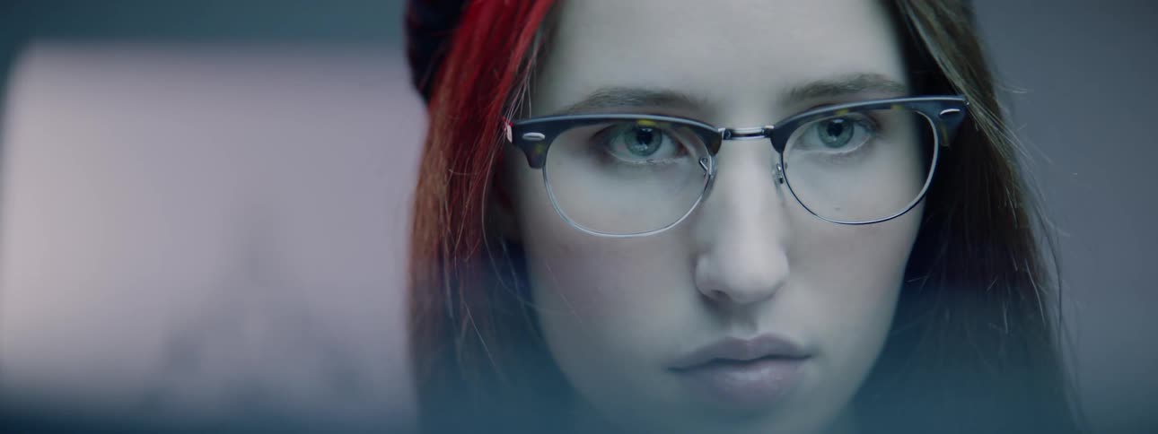 A woman in eyeglasses turning her head to look at different objects offscreen
