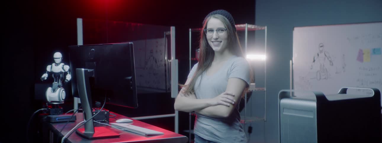 A woman stands in a technology room and poses for a portrait