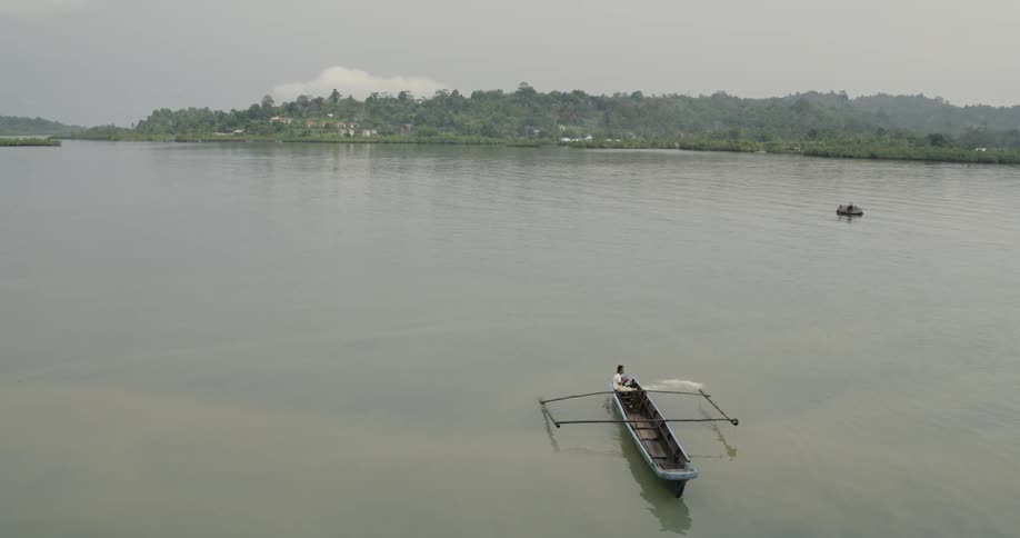 Fishing boat floats on lake calm waters near coast