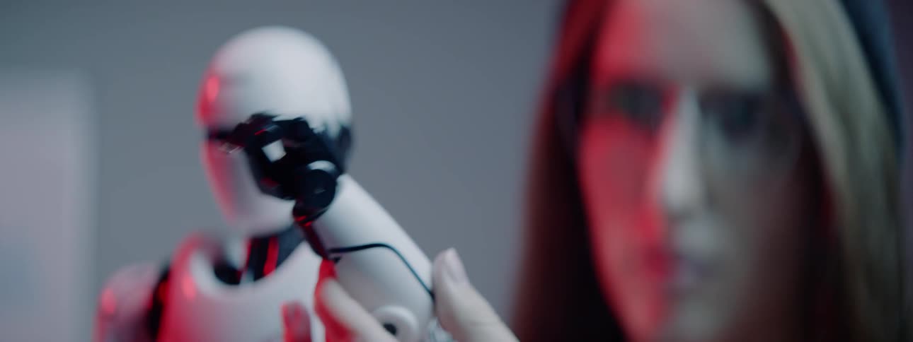A woman manipulates the arm of a small android robot