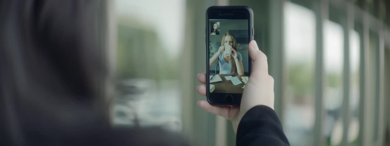 A woman holding a smart phone video calling a woman