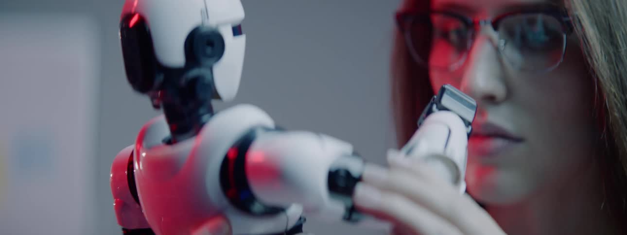 A teenager examines a small robot