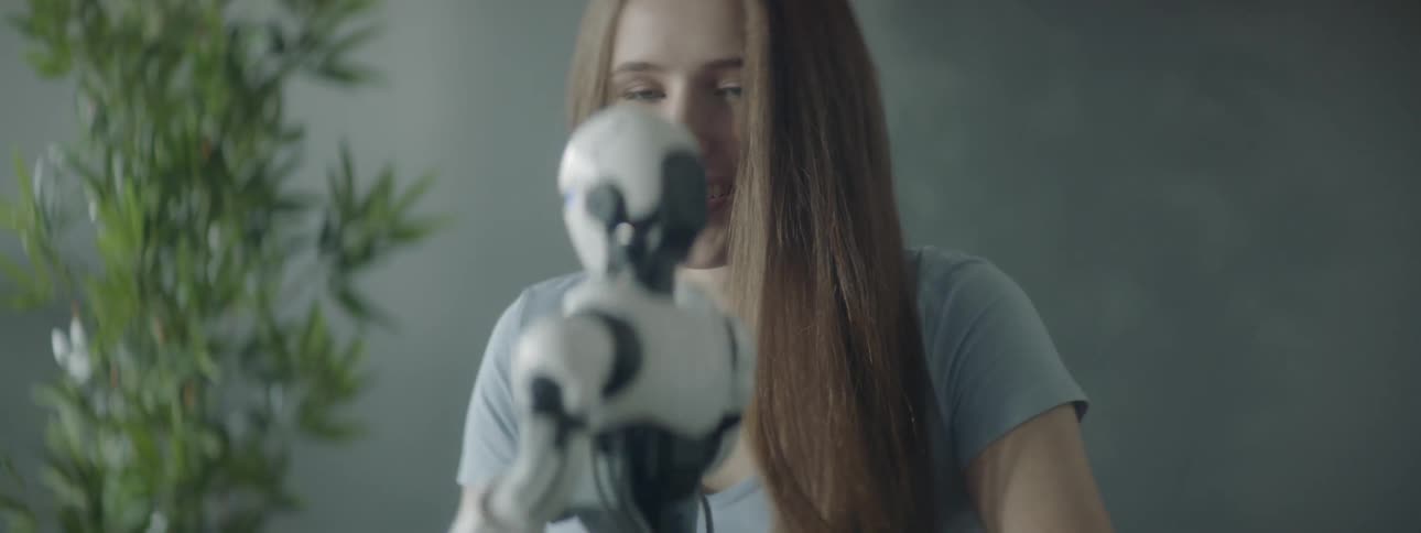 A woman smiling while watching a robot toy move around