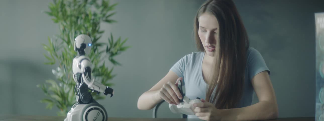 A woman picks up a remote controller for a toy robot