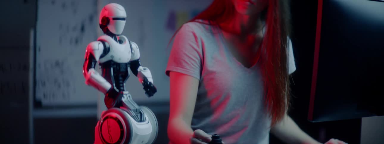 A woman works on computers and engineering equipment to program a robot