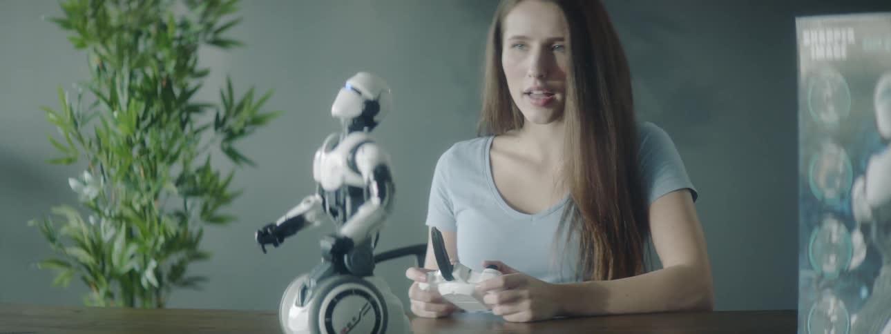 A young girl controls a robot with a remote control