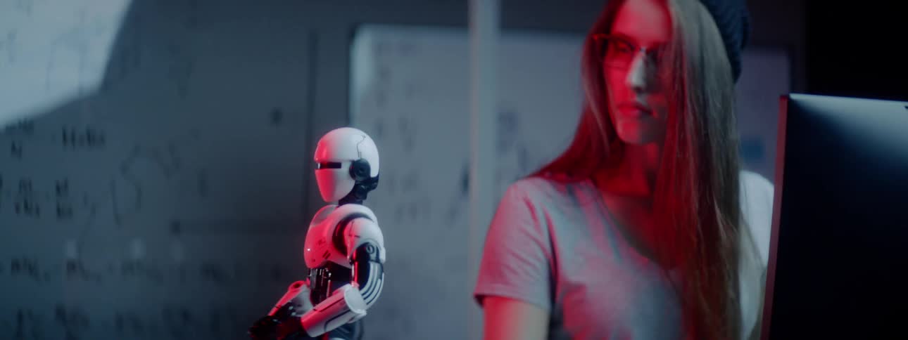 A woman works on a computer controlling a robot