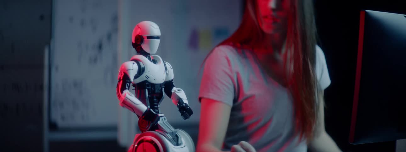 A woman typing into a computer then touching a control and turning a robot