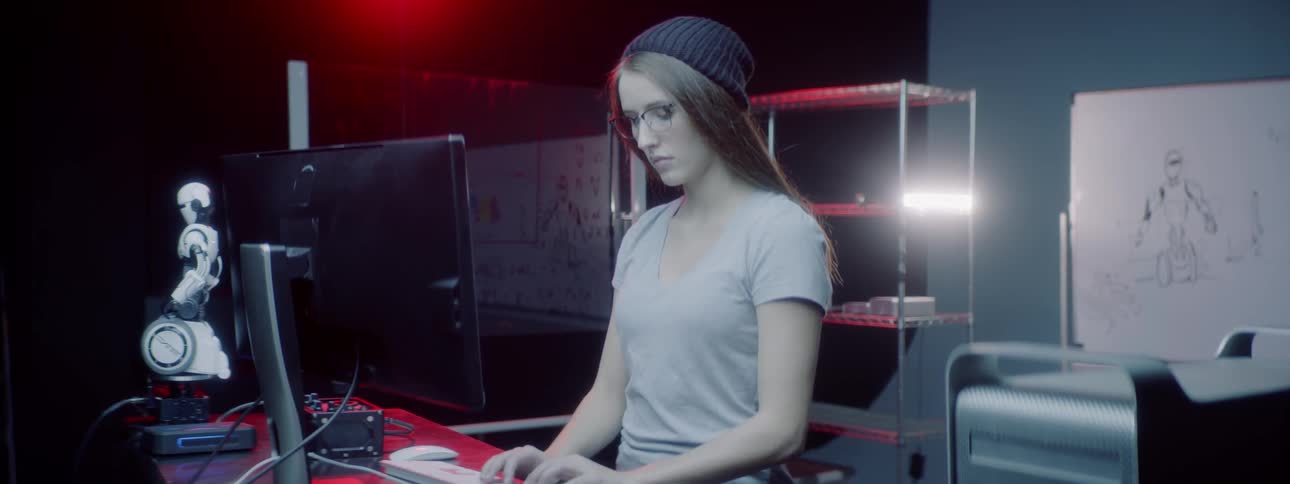 A young girl sits at her desk and works on her computer