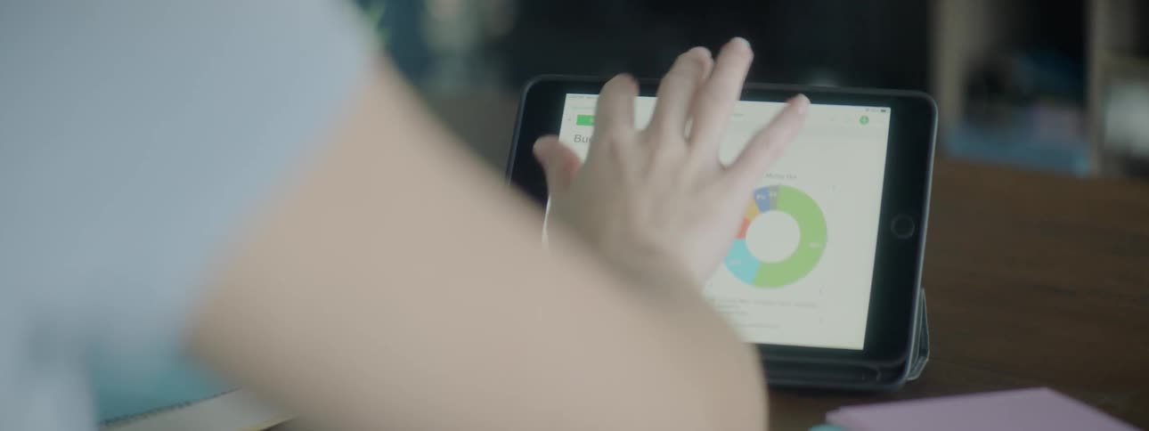 A woman works on a tablet sitting at a desk
