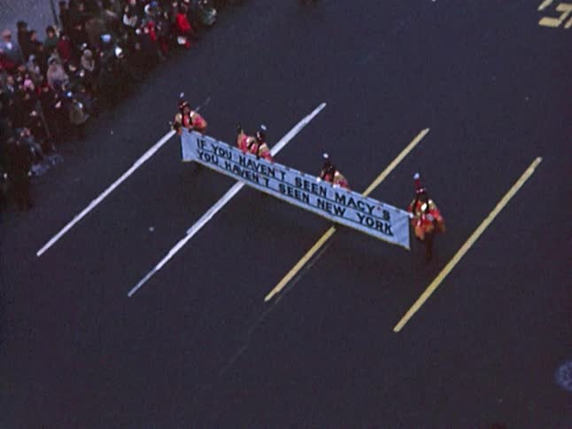 Four people in costume carry a banner in a parade