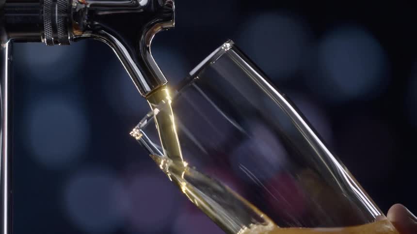 Beer from a tap pouring into a glass