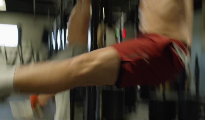 A man is hanging from a bar and touching his toes to his fingers