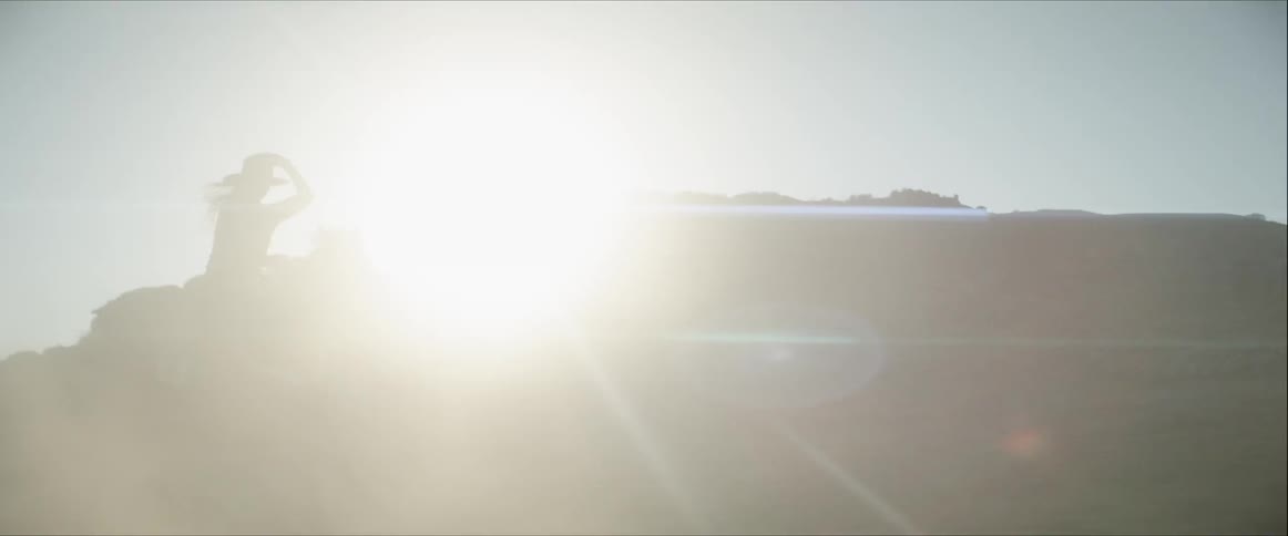 A woman rides a horse through a dusty field
