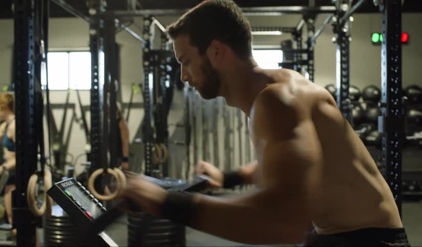 A muscular male pumps his arms back and forth as he exercises on a body rider style exercise bike